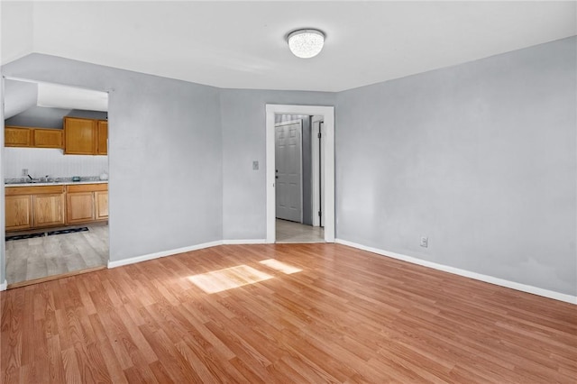 empty room featuring sink, vaulted ceiling, and light hardwood / wood-style floors