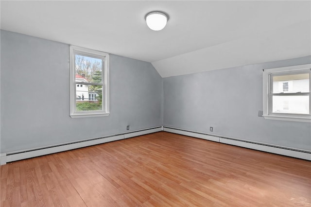 bonus room with a baseboard heating unit, a wealth of natural light, vaulted ceiling, and light wood-type flooring