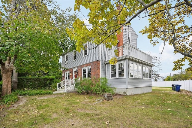 back of house featuring a yard and a balcony