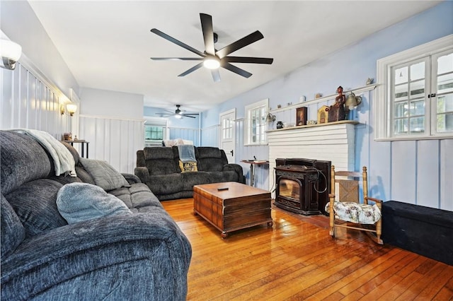 living room featuring hardwood / wood-style flooring, ceiling fan, plenty of natural light, and a wood stove