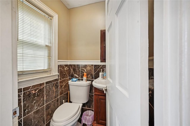 bathroom featuring a wealth of natural light, vanity, toilet, and tile walls