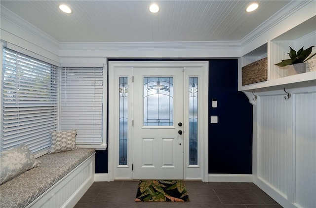 mudroom with dark tile patterned floors and crown molding