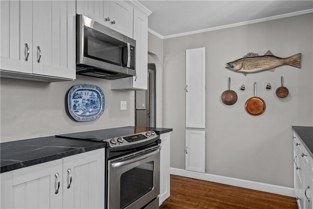 kitchen with dark hardwood / wood-style flooring, white cabinets, stainless steel appliances, and ornamental molding