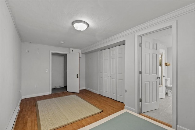 unfurnished bedroom with light hardwood / wood-style floors, baseboard heating, and a closet