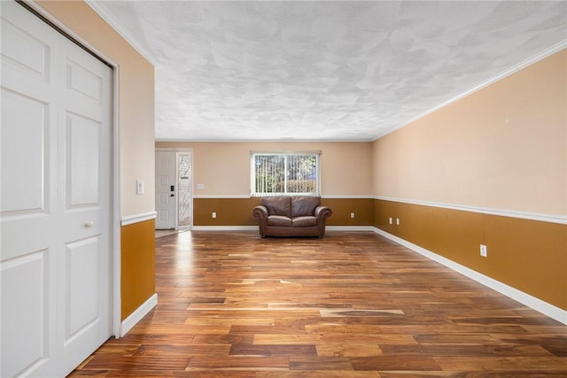 unfurnished room with hardwood / wood-style flooring, crown molding, and a textured ceiling