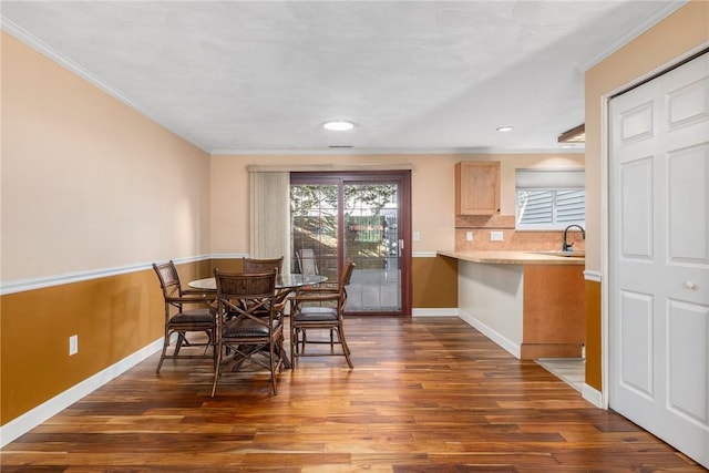 dining area with crown molding, dark wood-type flooring, and sink