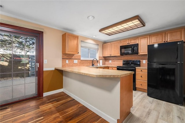 kitchen with crown molding, kitchen peninsula, sink, and black appliances