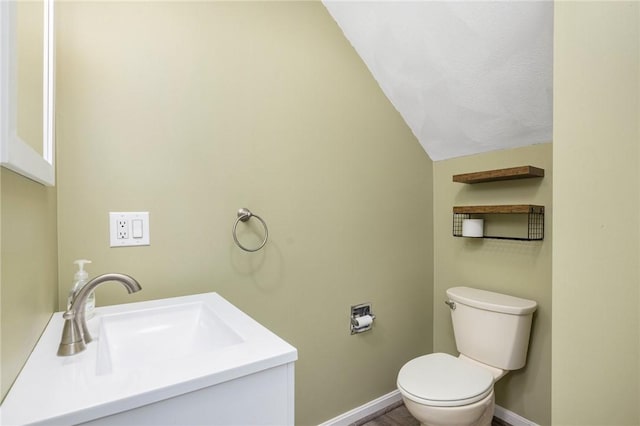 bathroom with vaulted ceiling, vanity, and toilet