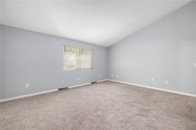 carpeted empty room featuring vaulted ceiling