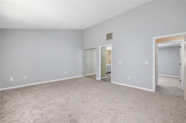 unfurnished bedroom featuring carpet, a towering ceiling, and connected bathroom