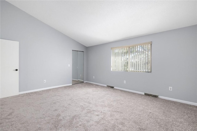 empty room featuring vaulted ceiling and carpet