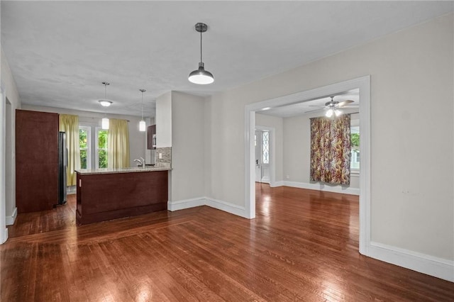 kitchen featuring ceiling fan, sink, dark hardwood / wood-style flooring, kitchen peninsula, and decorative light fixtures