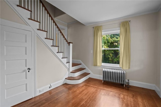 stairs featuring hardwood / wood-style floors and radiator