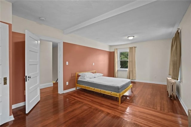 bedroom with beam ceiling, radiator, and hardwood / wood-style floors