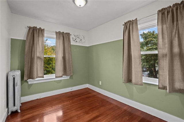 unfurnished room featuring radiator heating unit and hardwood / wood-style flooring