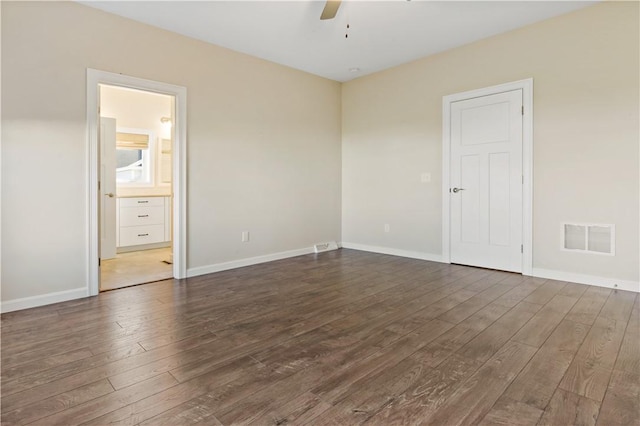 unfurnished bedroom with connected bathroom, ceiling fan, and dark wood-type flooring