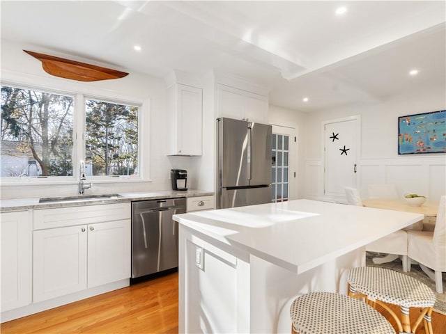 kitchen with white cabinets, a center island, sink, and appliances with stainless steel finishes