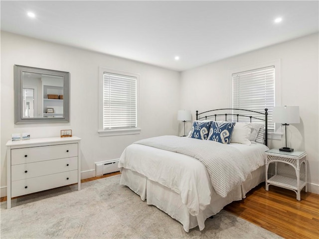 bedroom with a baseboard radiator and light hardwood / wood-style floors