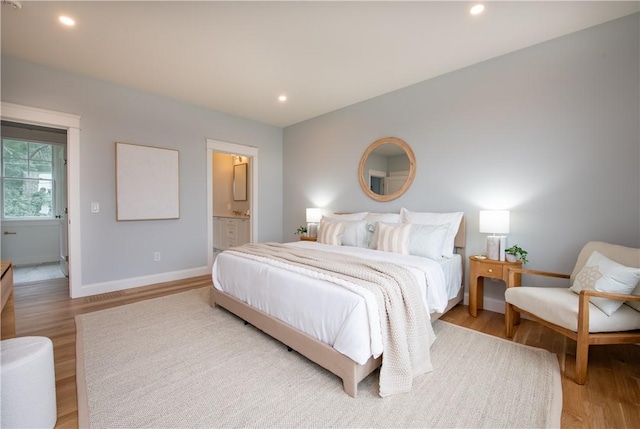 bedroom with ensuite bathroom and light wood-type flooring