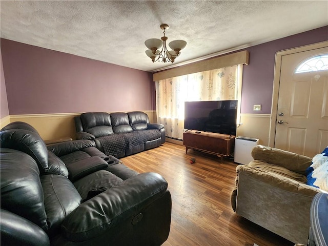 living room featuring hardwood / wood-style flooring, a notable chandelier, a healthy amount of sunlight, and a baseboard radiator