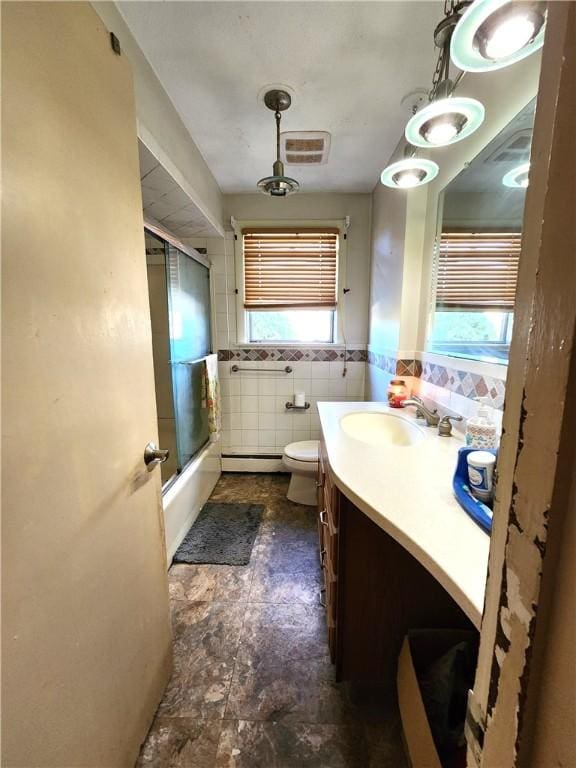 full bathroom with vanity, toilet, combined bath / shower with glass door, and tile walls