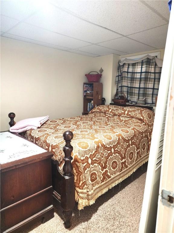 carpeted bedroom featuring a drop ceiling