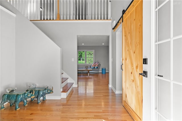 foyer entrance featuring a towering ceiling, light wood-type flooring, and a barn door