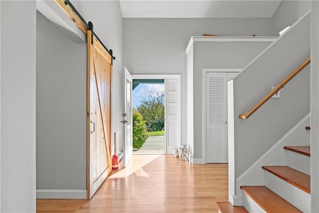 foyer with a barn door and light hardwood / wood-style flooring