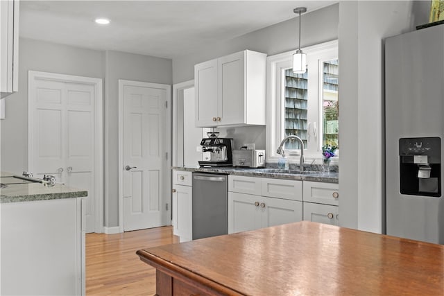 kitchen with stainless steel appliances, sink, white cabinetry, light hardwood / wood-style flooring, and hanging light fixtures