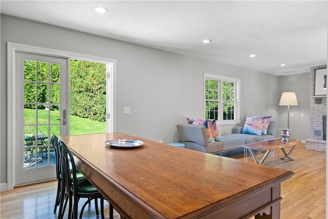 dining space with a brick fireplace and light hardwood / wood-style flooring