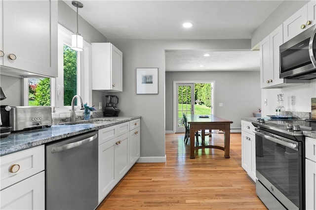 kitchen featuring pendant lighting, light wood-type flooring, white cabinets, appliances with stainless steel finishes, and sink