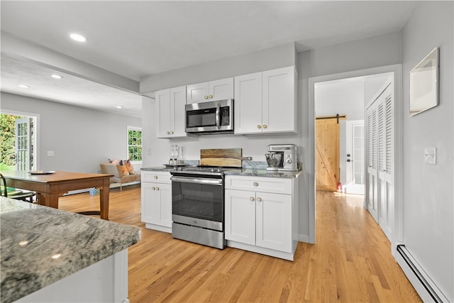 kitchen with stainless steel appliances, a barn door, white cabinets, and baseboard heating