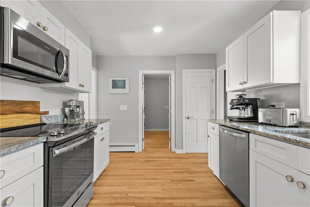 kitchen featuring appliances with stainless steel finishes, a baseboard radiator, dark stone countertops, and white cabinetry