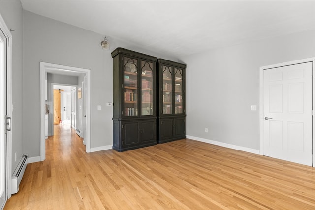 empty room with a baseboard radiator and light hardwood / wood-style floors