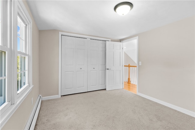 unfurnished bedroom with a baseboard heating unit, a closet, and light carpet