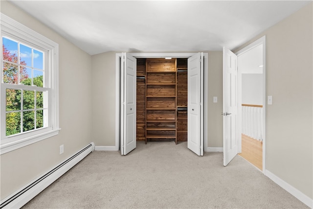 unfurnished bedroom featuring a baseboard radiator, a closet, multiple windows, and light colored carpet