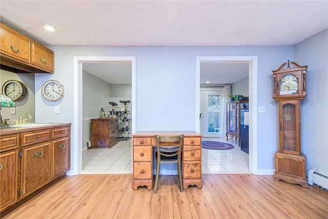 kitchen featuring baseboard heating, sink, and light hardwood / wood-style flooring