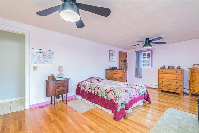 bedroom with hardwood / wood-style floors, baseboard heating, and ceiling fan