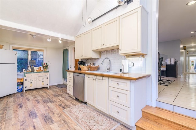 kitchen featuring light wood-type flooring, backsplash, sink, white refrigerator, and dishwasher