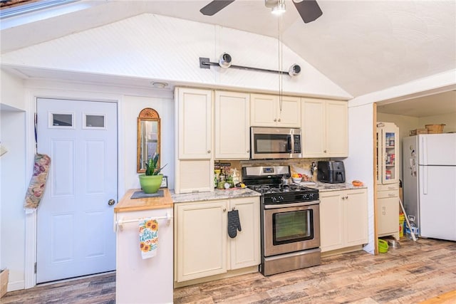 kitchen featuring lofted ceiling, light wood-type flooring, appliances with stainless steel finishes, and tasteful backsplash