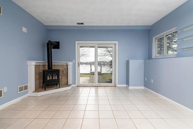 unfurnished living room featuring light tile patterned floors and a wood stove