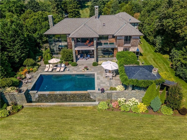 outdoor pool featuring a lawn and a patio area