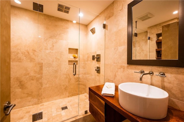 bathroom with a stall shower, tile walls, and vanity