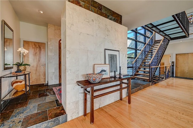 foyer entrance featuring stairs, wood finished floors, tile walls, and floor to ceiling windows