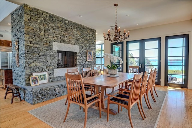 dining area featuring french doors, a notable chandelier, a fireplace, and wood finished floors