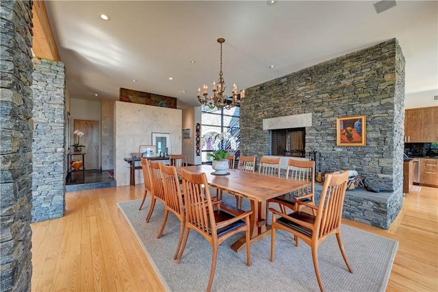 dining area with a chandelier, light wood finished floors, a fireplace, and recessed lighting