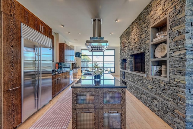 kitchen featuring light wood-type flooring, dark countertops, built in features, and built in refrigerator