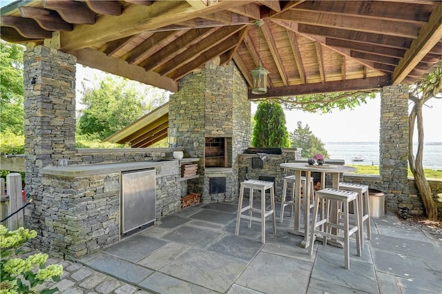 view of patio / terrace with a gazebo, exterior kitchen, a fireplace, and outdoor dining space