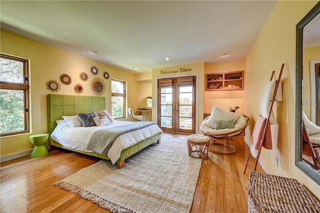 bedroom with access to outside, baseboards, wood finished floors, and french doors