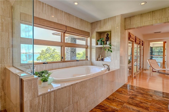 full bath featuring a bath, visible vents, tile walls, and recessed lighting